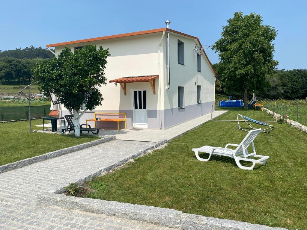 une chaise blanche sur l'herbe devant une maison dans l'établissement Casa da Nora, à Póvoa de Lanhoso