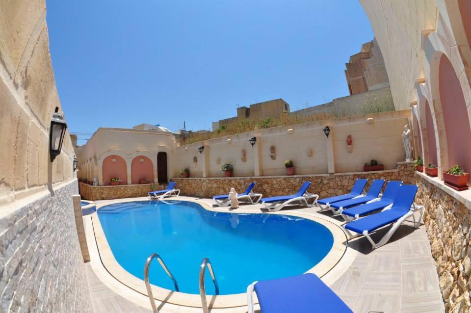 una piscina con sedie a sdraio blu e un edificio di 6 Bedroom Farmhouse with Private Pool in Zebbug Gozo a Żebbuġ