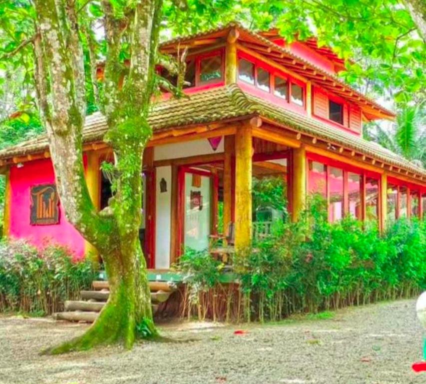 uma casa vermelha com uma árvore em frente em Thai Pousada em Ubatuba