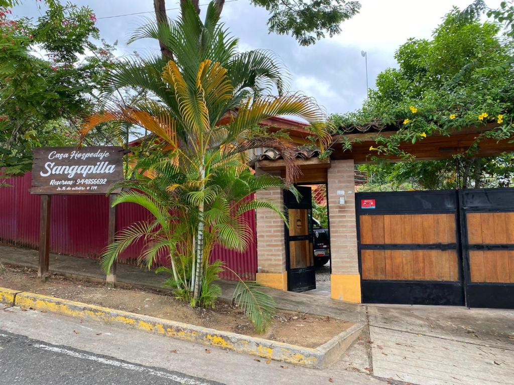 a palm tree in front of a building with a sign at Casa Hospedaje Sangapilla in Lamas