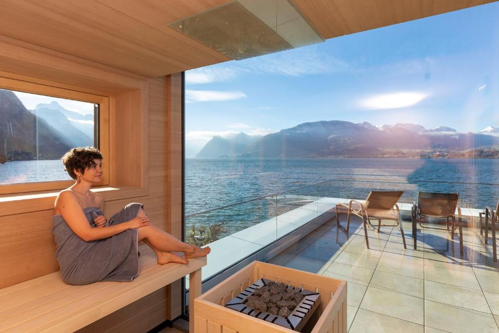 un uomo seduto su un balcone con vista sull'acqua di Seegasthof Hois'n Wirt - Hotel mit Wellnessbereich a Gmunden