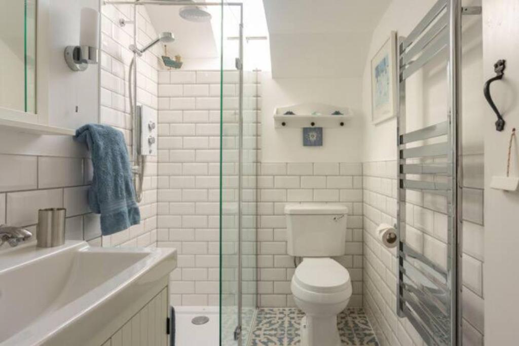 a white bathroom with a toilet and a sink at Cosycot in Gorran Haven