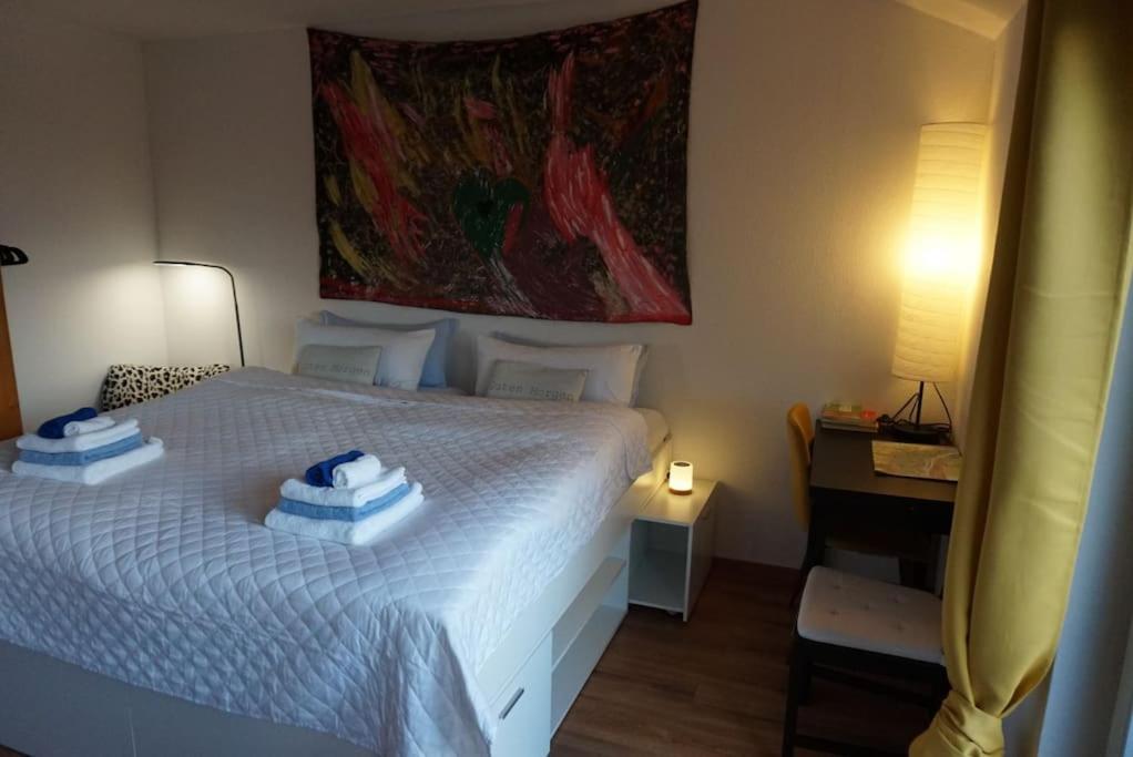 a bedroom with a white bed and a painting on the wall at Gästewohnung von J&O am Fluss. in Jork