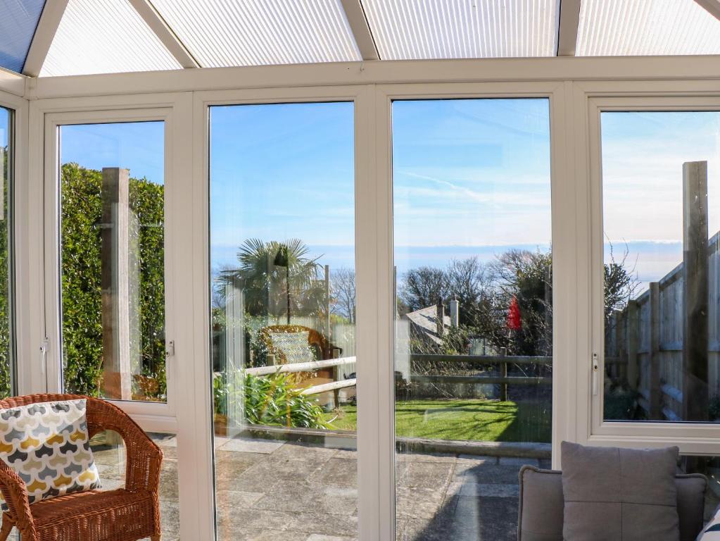 a conservatory with sliding glass doors looking out onto a garden at Saltwater Cottage in Ventnor