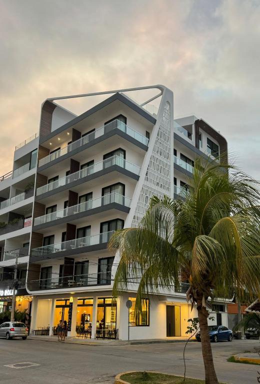 un grande edificio con una palma di fronte di Alizee Tower a Playa del Carmen