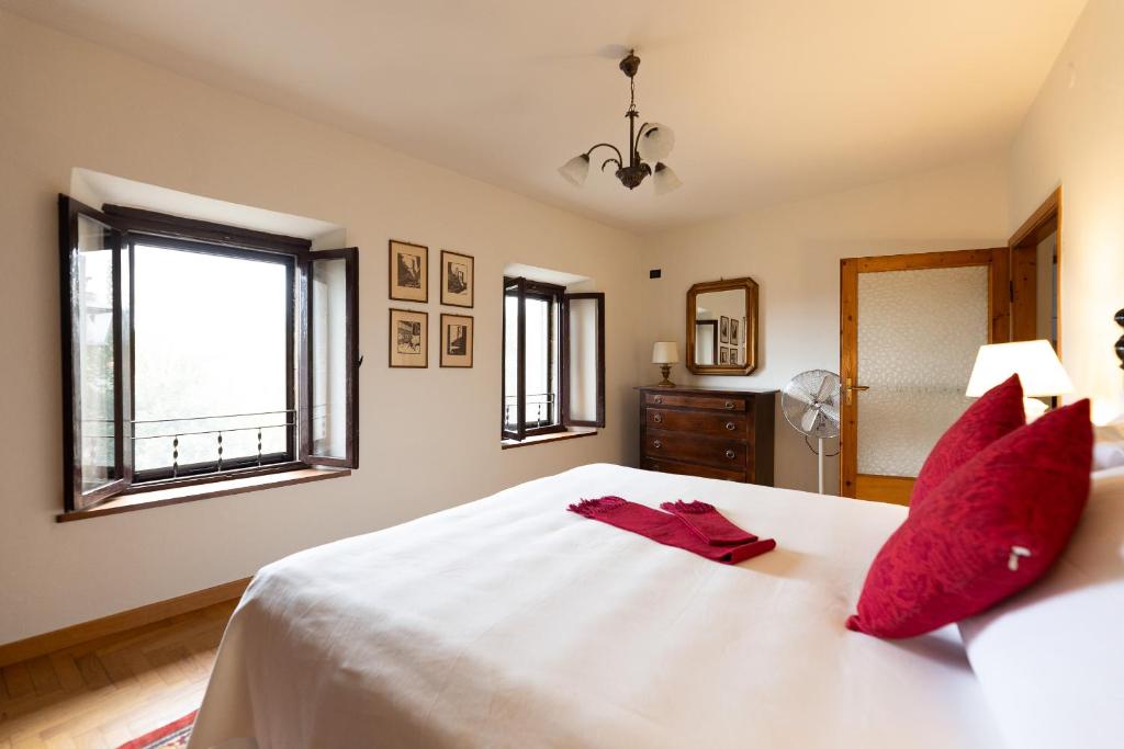 1 dormitorio con 1 cama blanca grande con almohadas rojas en Borgo di Porciano Casa Elisabetta en Stia
