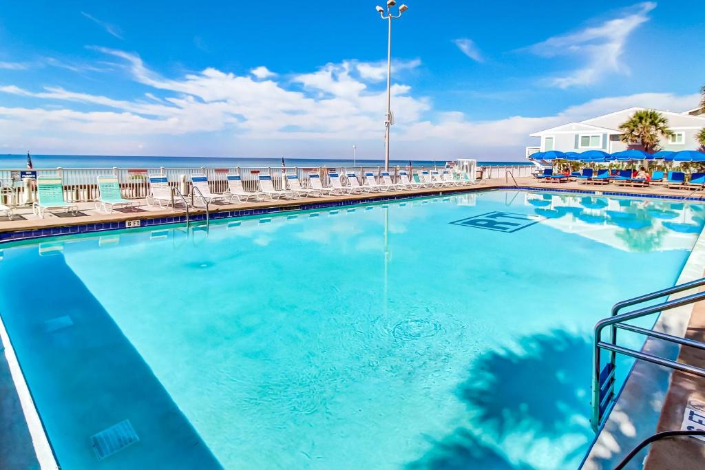uma piscina com cadeiras e o oceano ao fundo em Regency Towers em Panama City Beach
