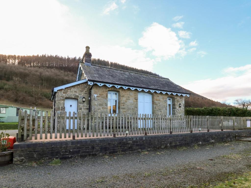 a small stone house with a fence at Railway Station Cottage in Llandrindod Wells
