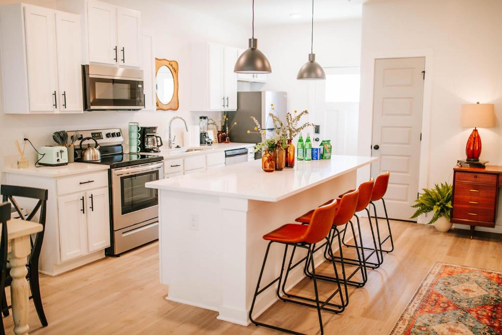 a kitchen with white cabinets and a large island with bar stools at Artist Retreat - Near Downtown, Stadium, Campus in Athens