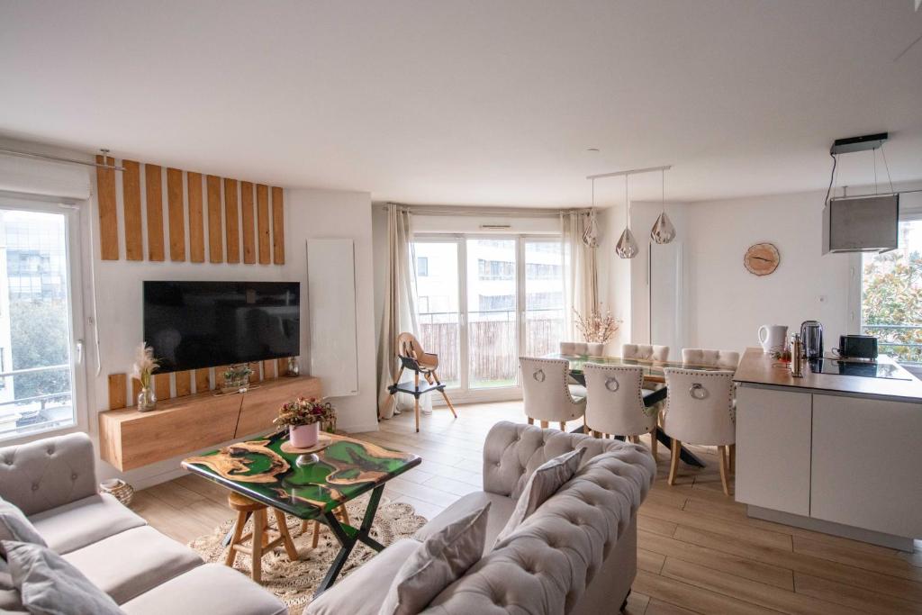 uma sala de estar com um sofá e uma mesa em ELISE DE ROCHE Équipé Balcon Parking RER B em Le Bourget