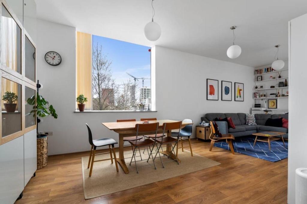 a dining room and living room with a table and chairs at Luxury modern flat near ExCel, 02 & Canary Wharf in London