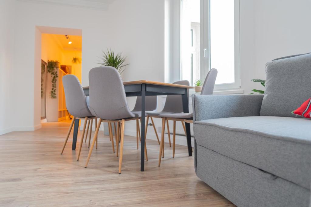 - un salon avec une table, des chaises et un canapé dans l'établissement Torun Bridge Apartament, à Toruń