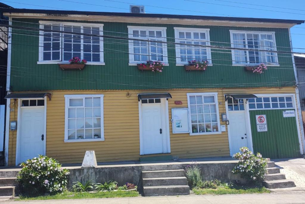 a green and yellow house with white doors and windows at Hostal Trautmann in Puerto Montt