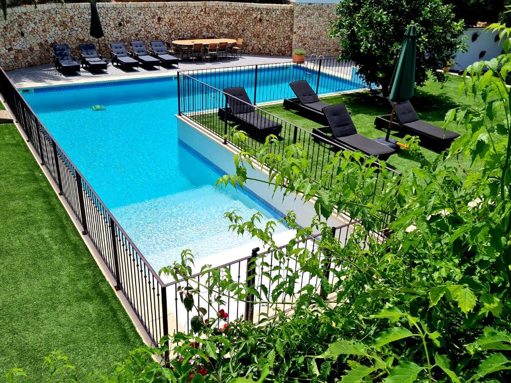 an image of a swimming pool with chairs in a yard at Galdana's House in Cala Galdana