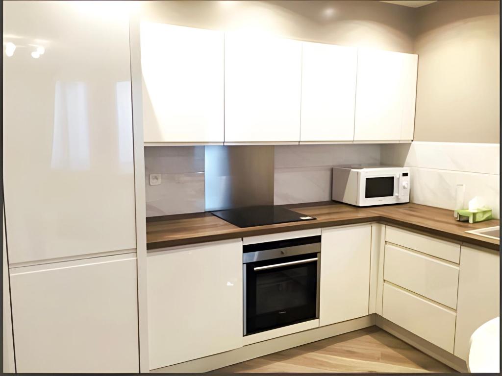 a kitchen with white cabinets and a microwave at Appartement moderne au centre de Paris, 3ème in Paris