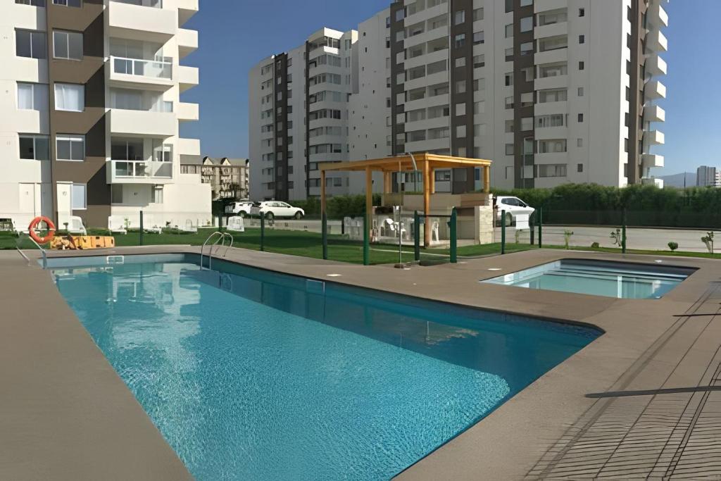 a swimming pool in a building with tall buildings at Condominio Pacífico III in La Serena