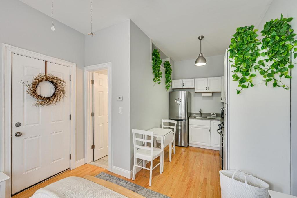 a kitchen with white cabinets and a table and chairs at Cozy Somerville Studio 2 Mi to Boston, Walk to T! in Somerville