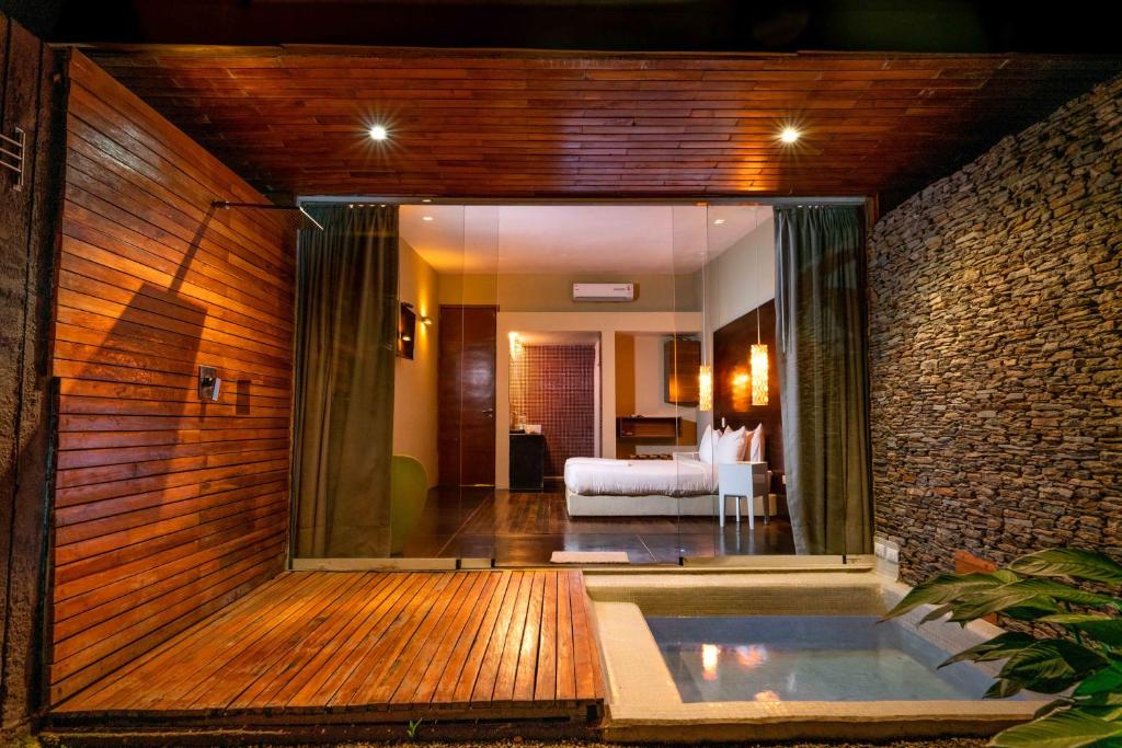 a bathroom with a tub in a room with a bedroom at Cacaoni Hotel in Puerto Colombia