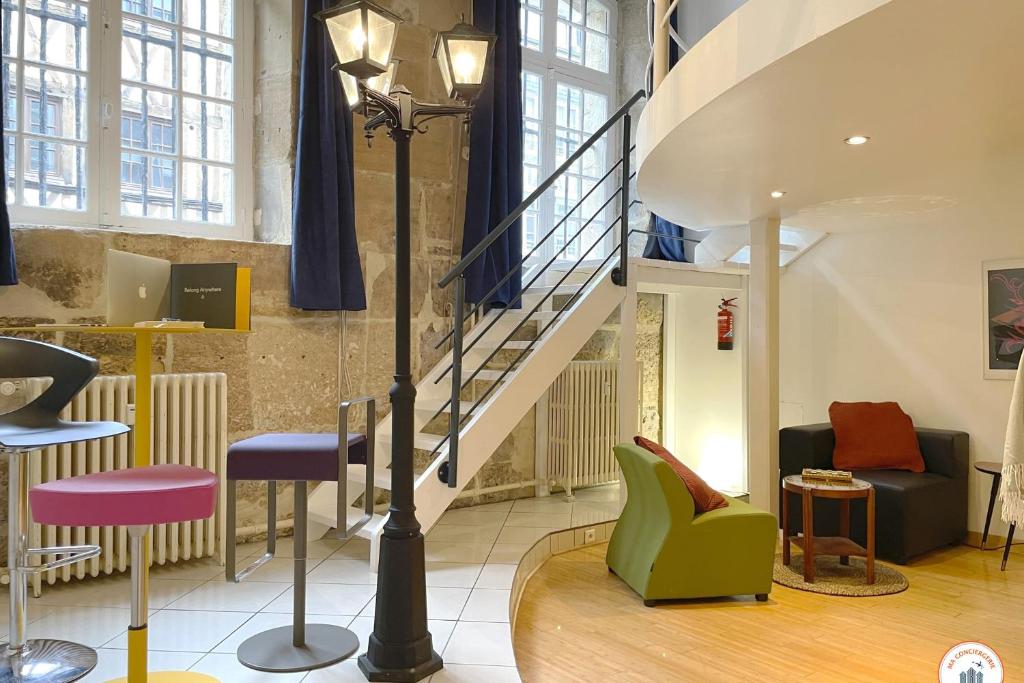 a lobby with a staircase and some chairs and tables at Loft de l'Artiste - Parking - Standing in Rouen