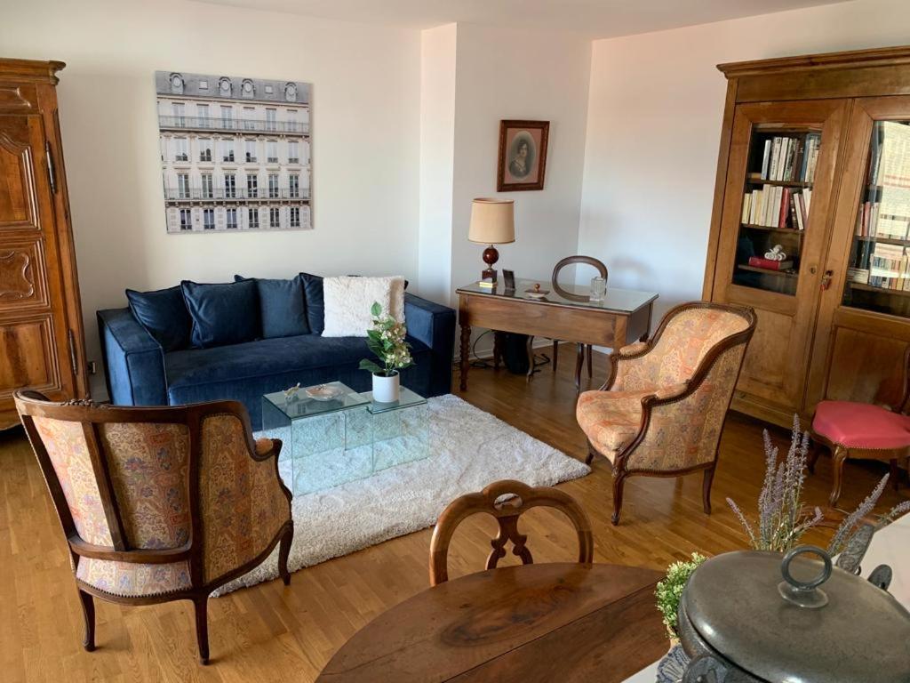 ein Wohnzimmer mit einem blauen Sofa und einem Tisch in der Unterkunft PARIS 10 ' BASTILLE (CHARENTON LE PONT) in Charenton-le-Pont