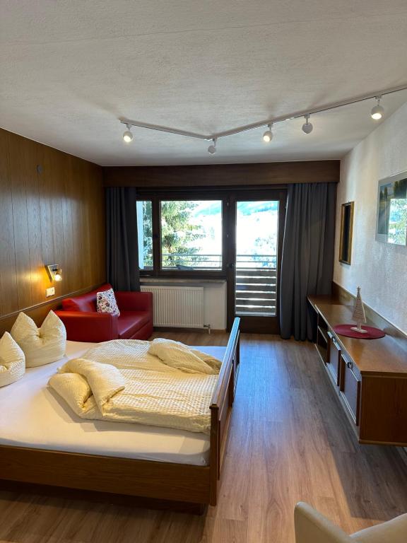 a bedroom with a large bed and a red couch at Appartements Dobler - s'Zischgn in Arzl im Pitztal