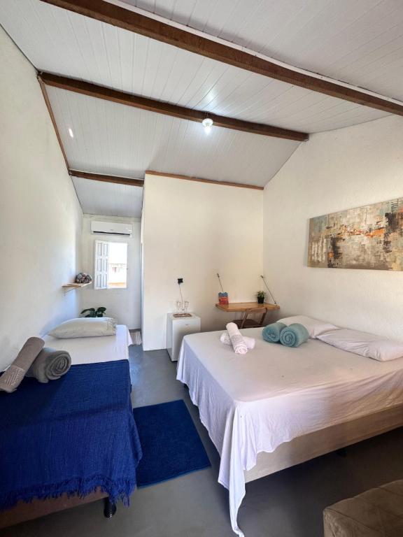 2 łóżka w pokoju z białymi ścianami w obiekcie Vila Cajuzinho w mieście Caraíva
