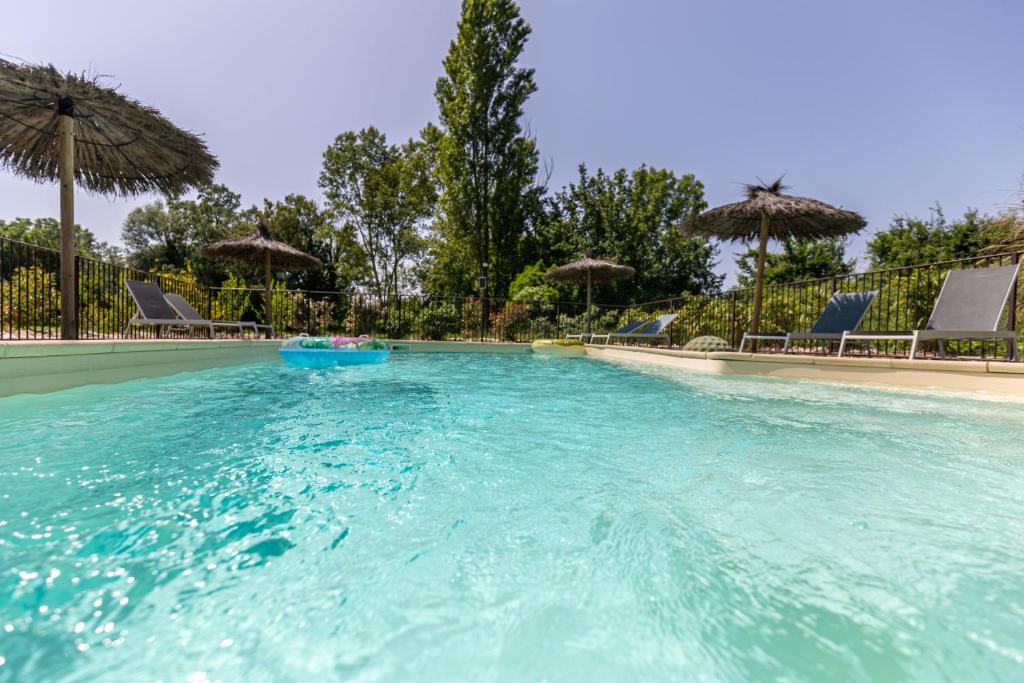 una gran piscina con sillas y sombrillas en Auberge Gardoise, en Vallérargues