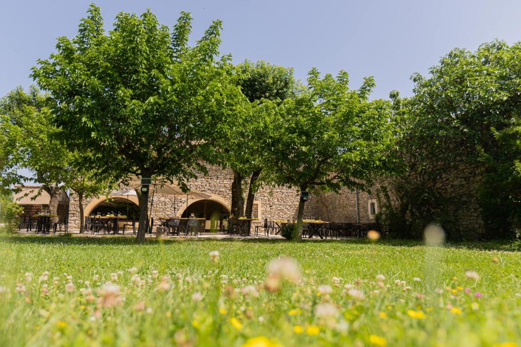 een bakstenen gebouw met bomen en een grasveld bij Auberge Gardoise in Vallérargues