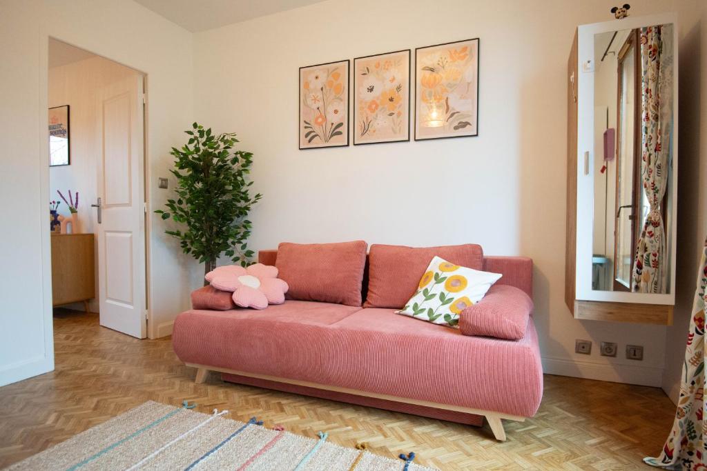 - un salon avec un canapé rose et des oreillers dans l'établissement Alegria - Disney 10min - Paris - Vallée Village - Parking, à Chessy