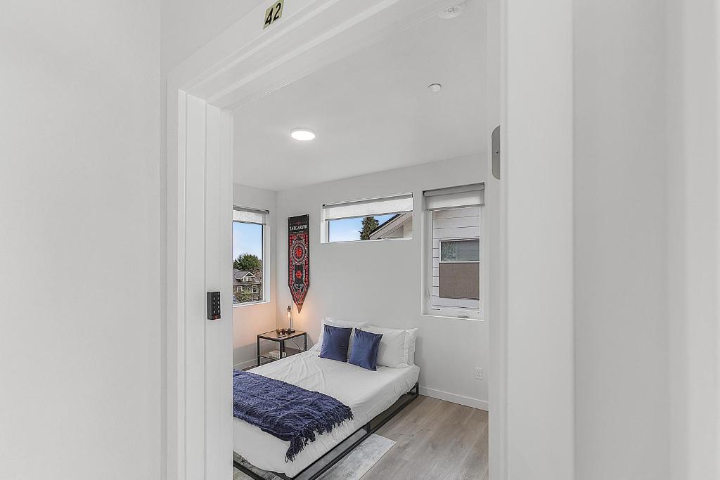 a white bedroom with a bed and two windows at Tides of Seasmoke Suite in Seattle
