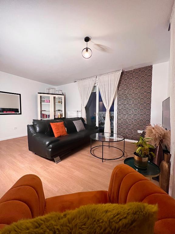 a living room with a black leather couch and a table at SSP Suites- Cosy &amp; Bel appartement 4 pièces 3 chambres 90M2 avec balcon in Épinay-sur-Seine