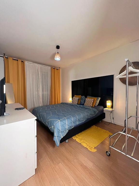 a bedroom with a bed and a desk with a television at SSP Suites- Cosy &amp; Bel appartement 4 pièces 3 chambres 90M2 avec balcon in Épinay-sur-Seine