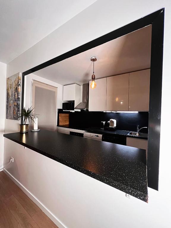 a kitchen with a black and white counter top at SSP Suites- Cosy &amp; Bel appartement 4 pièces 3 chambres 90M2 avec balcon in Épinay-sur-Seine