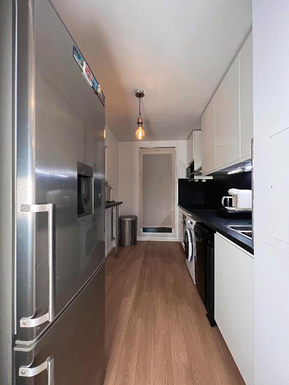 a large kitchen with a stainless steel refrigerator at SSP Suites- Cosy &amp; Bel appartement 4 pièces 3 chambres 90M2 avec balcon in Épinay-sur-Seine