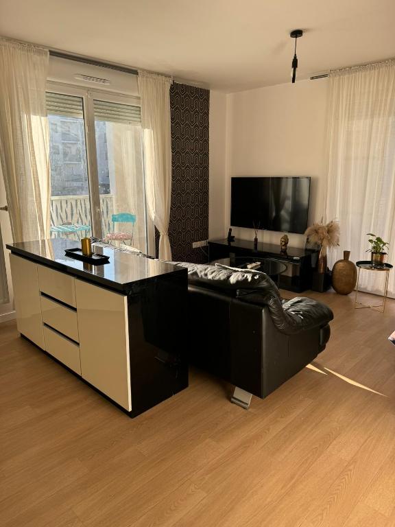 a living room with a black couch and a flat screen tv at SSP Suites- Cosy &amp; Bel appartement 4 pièces 3 chambres 90M2 avec balcon in Épinay-sur-Seine