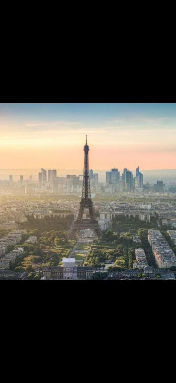 a view of the eiffel tower at sunset at SSP Suites- Cosy &amp; Bel appartement 4 pièces 3 chambres 90M2 avec balcon in Épinay-sur-Seine