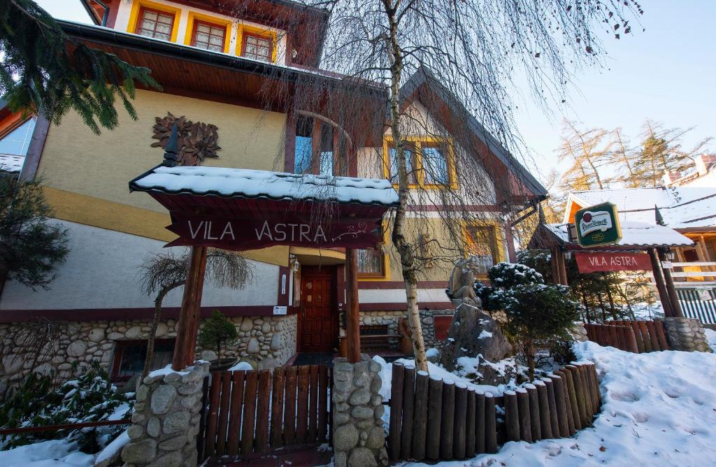 a building with a sign in the snow at Wellness Vila Astra in Stará Lesná