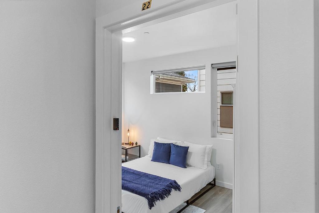 a white bedroom with a bed with blue pillows at Balerion's Shadowed Suite in Seattle