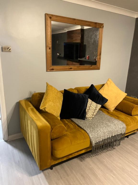 ein braunes Sofa im Wohnzimmer mit Spiegel in der Unterkunft Comfy Darlington Home in Darlington