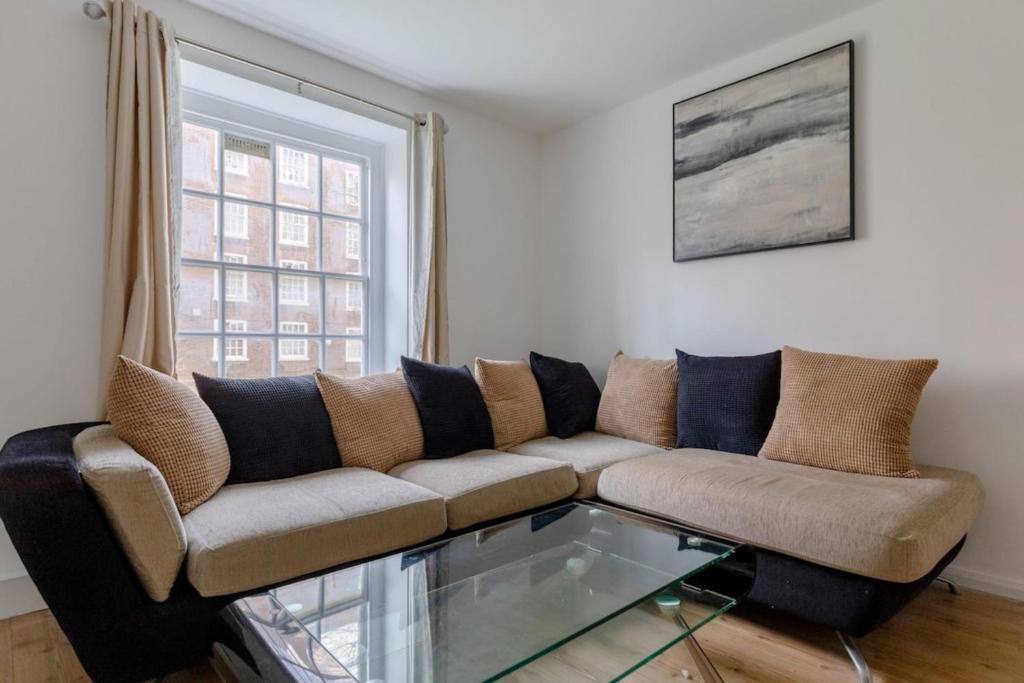 een woonkamer met een bank en een glazen tafel bij Inviting 2BD Flat 15 Minutes from Regents Park! in Londen