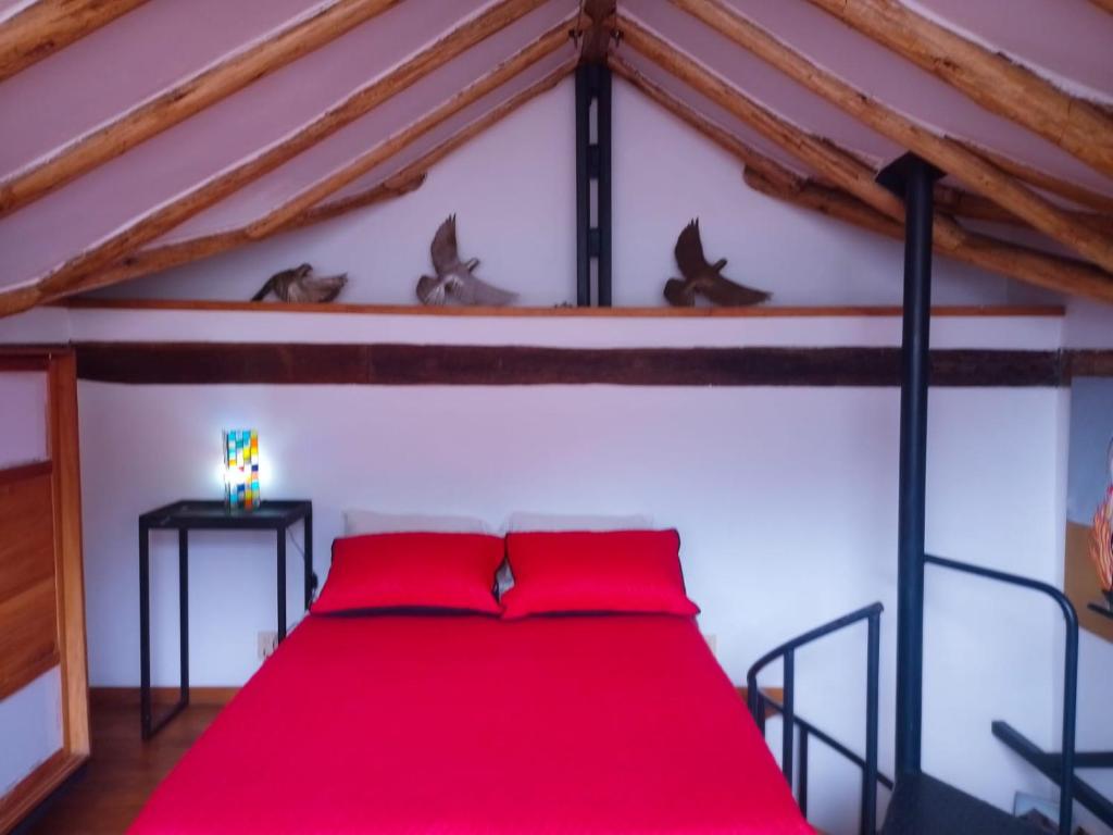 a bedroom with a red bed in a attic at Villa Monserrate Bed and Breakfast in Bogotá