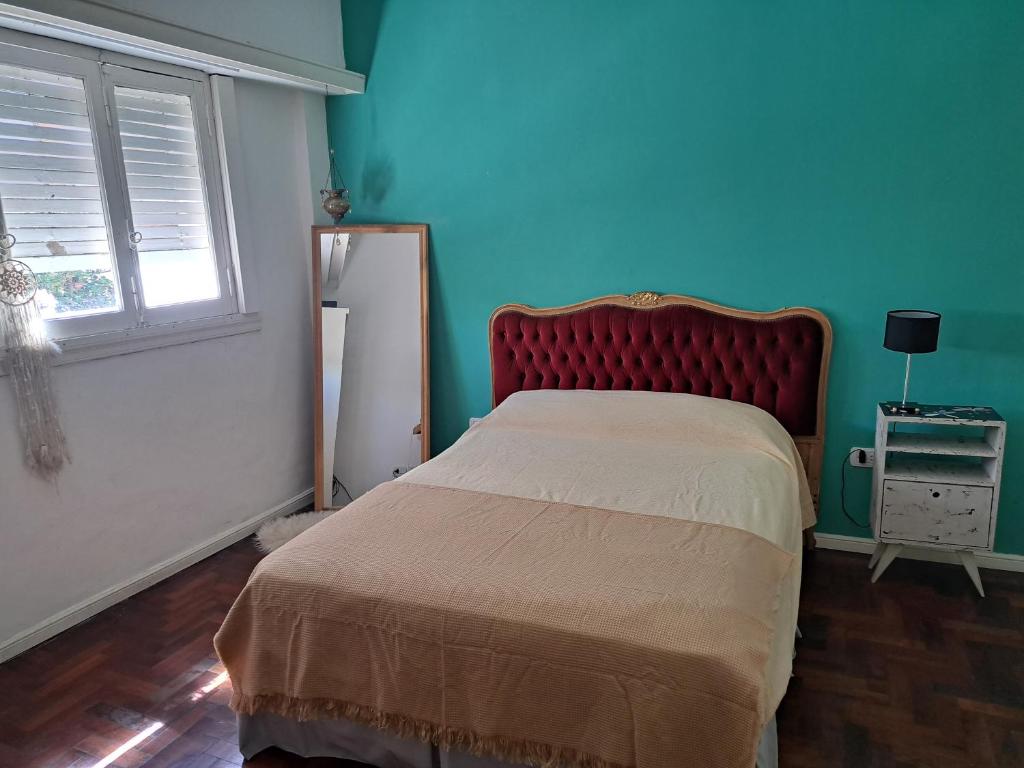 um quarto com uma cama com uma cabeceira vermelha e uma janela em La casita de boedo em Buenos Aires