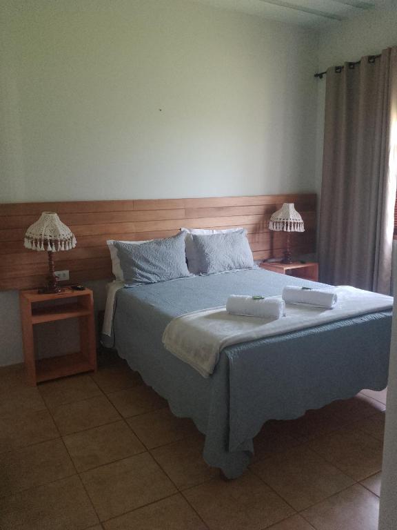 een slaapkamer met een bed met twee handdoeken erop bij Pousada Vivenda Letícia in Prados