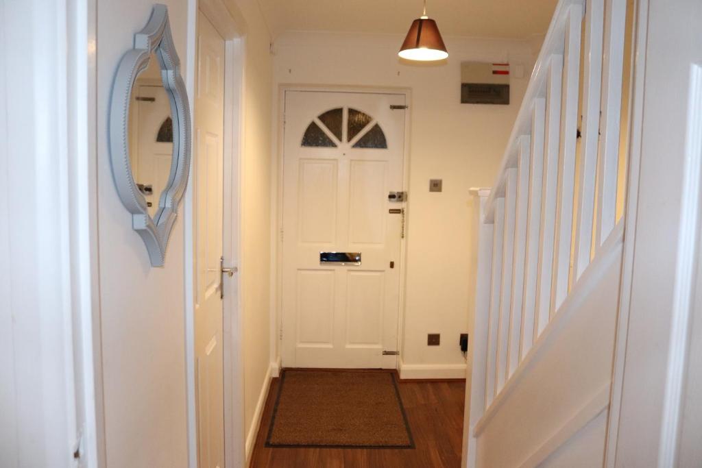 einen Flur mit einer weißen Tür und einer Treppe in der Unterkunft Dove's Place in historic Rochester with Parking in Strood