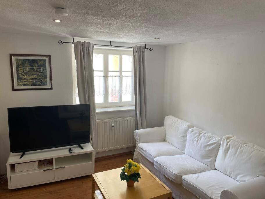 ein Wohnzimmer mit einem weißen Sofa und einem Flachbild-TV in der Unterkunft Schöne 2 Zimmer Ferienwohnung in Ebern in Ebern