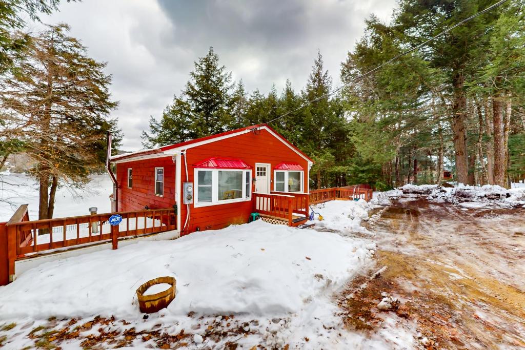 a red cabin with snow on the ground at Hermit Lake Retreat in Sanbornton