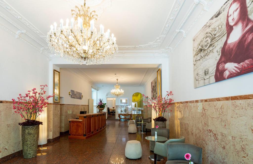 eine Lobby mit einem Kronleuchter, Stühlen und einem Tisch in der Unterkunft Leonardo Hotel Berlin KU'DAMM in Berlin