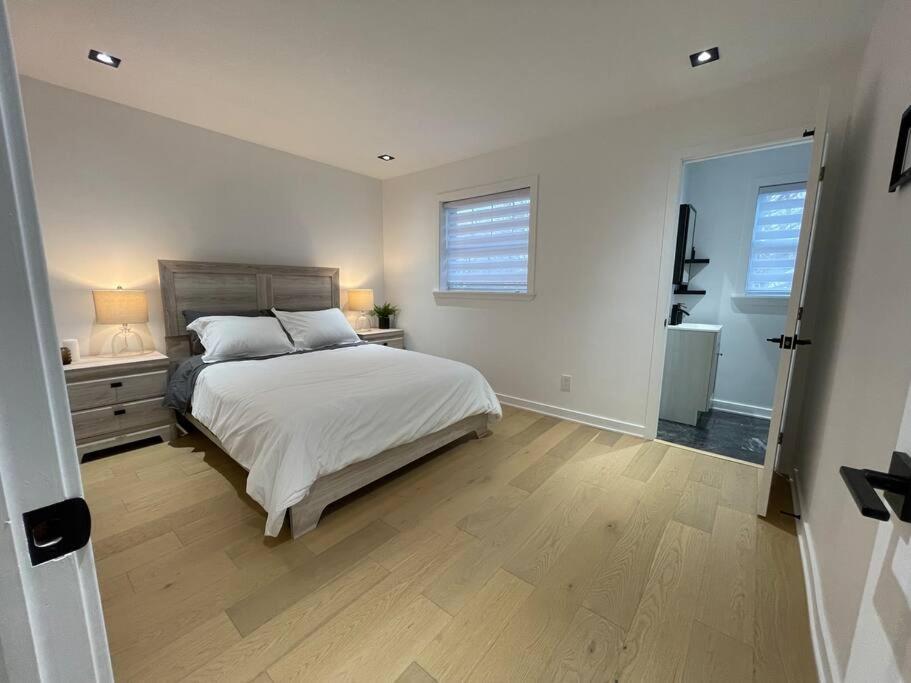 ein weißes Schlafzimmer mit einem Bett und einem Fenster in der Unterkunft Modern Home for 10+ with Hot Tub! in Ottawa
