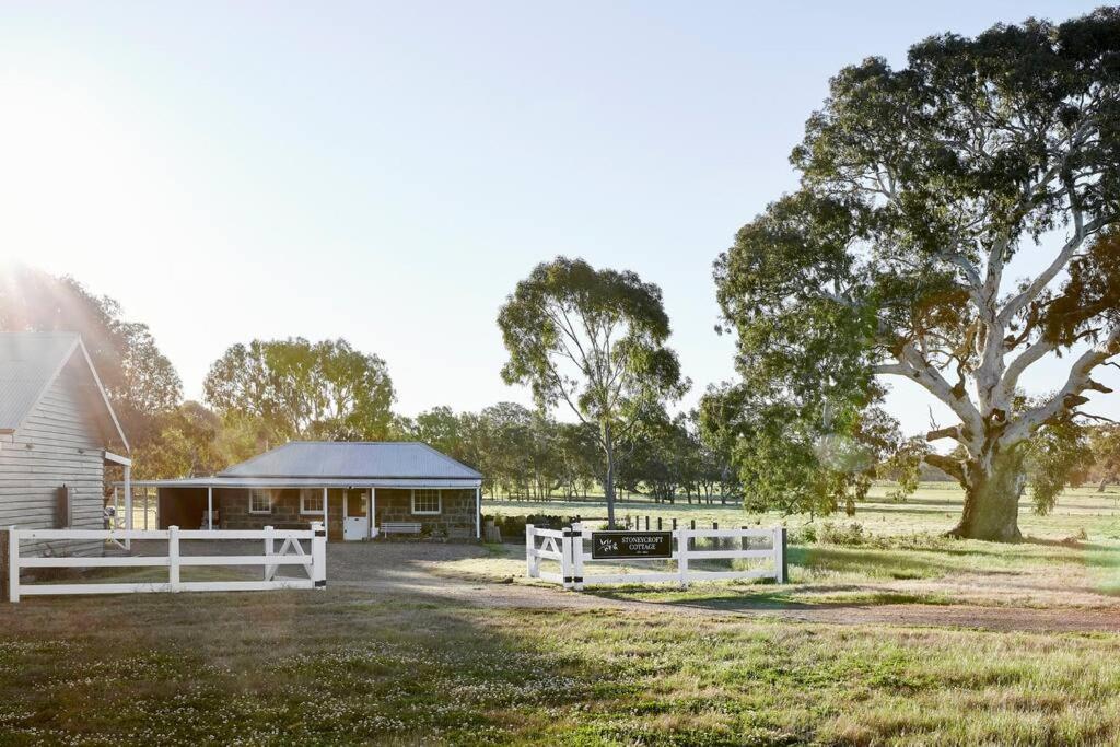 a house with a white fence in front of a field at Stoneycroft Cottage ~ Grampians Farm Stay 