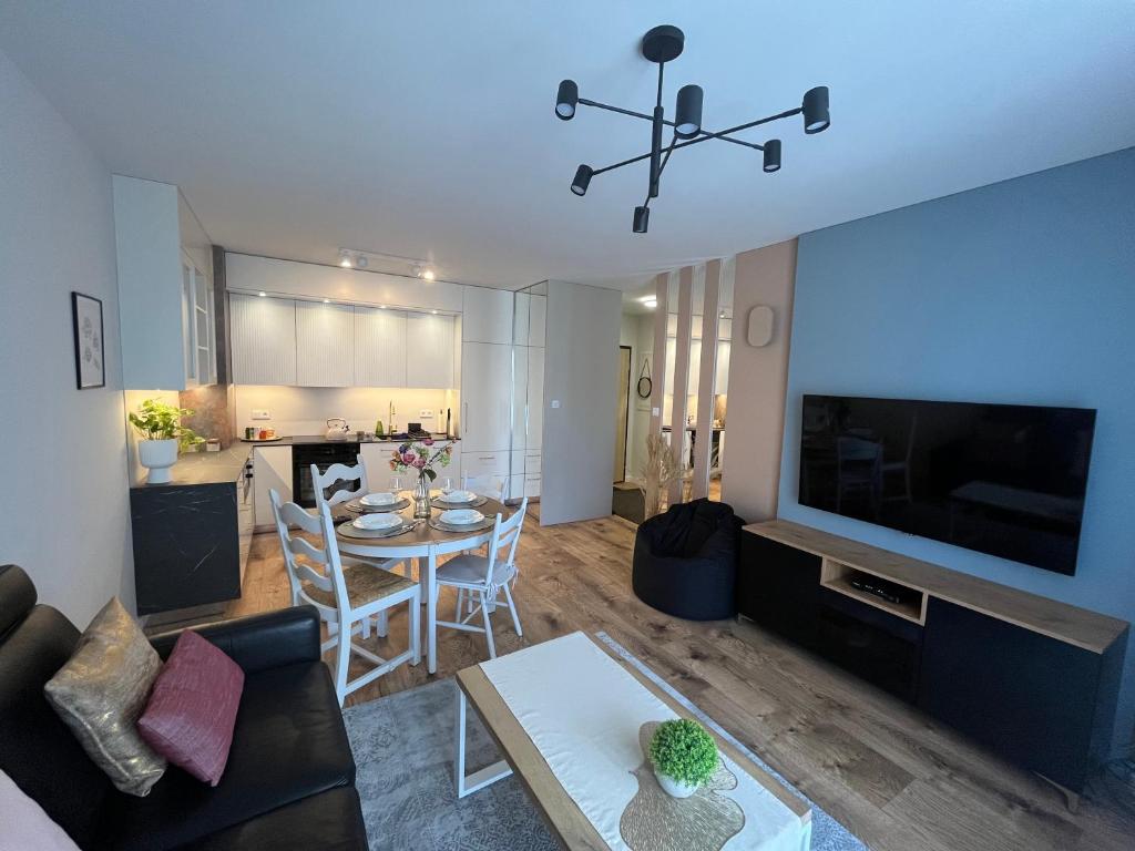 a living room with a table and a dining room at Apartament NOWE POJEZIERZE in Olsztyn